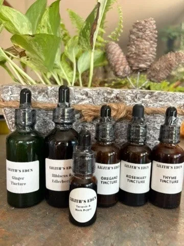 A row of amber and green dropper bottles of herbal tinctures labelled rosemary, thyme, oregano, ginger and elderberry