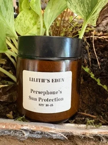 An amber jar labelled Persephone's Sun Protection among garden leaves